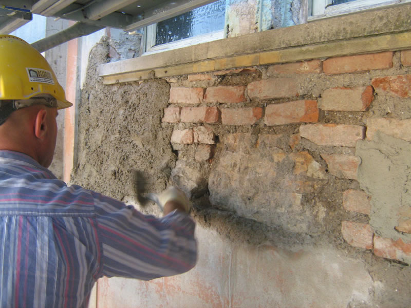 operaio esegue il risanamento di un edificio